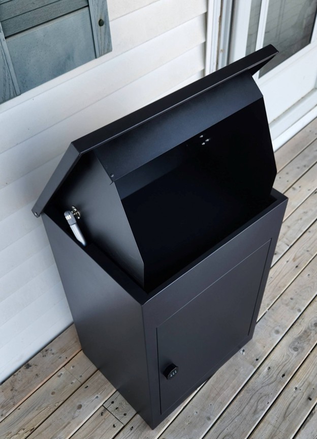 Picture5 - Toronto Bangla Town | Digital Bangla Weekly Magazine Black metal outdoor smoker/grill with the lid open, showing the smoking chamber and a lower storage cabinet on a wooden deck beside a house.