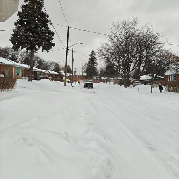 Picture7 - Toronto Bangla Town | Digital Bangla Weekly Magazine Snow-covered suburban street with a car parked in the distance and snow piles along the sidewalks.