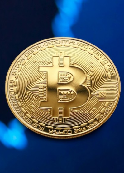 Picture1 - Toronto Bangla Town | Digital Bangla Weekly Magazine Close-up of a gold Bitcoin coin with the BTC symbol and circuit patterns, blue bokeh background.