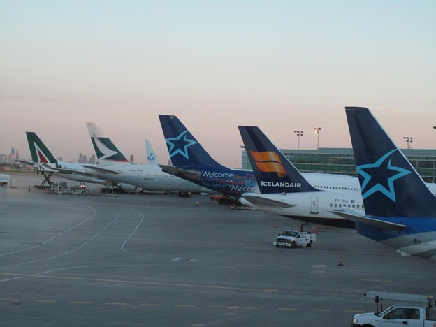 Picture2 - Toronto Bangla Town | Digital Bangla Weekly Magazine Several commercial airplanes parked at a terminal gate on the tarmac at sunset/early evening.