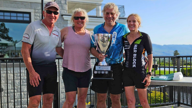 Picture7 - Toronto Bangla Town | Digital Bangla Weekly Magazine Four adults posing on a balcony with a large trophy, two men and two women in athletic gear, smiling at the camera with mountains in the background.