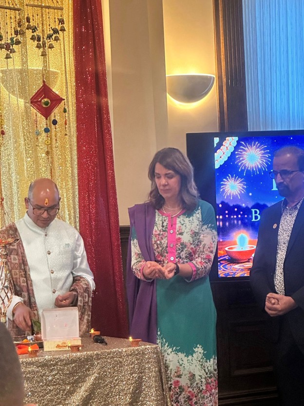 Picture8 - Toronto Bangla Town | Digital Bangla Weekly Magazine Man in white traditional attire and a woman in a floral dress stand beside a glittery table with lit candles during a ceremony.