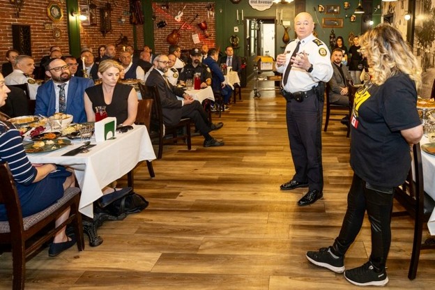 Picture1 - Toronto Bangla Town | Digital Bangla Weekly Magazine Police or security official speaks to a seated audience at a formal dinner in a restaurant setting.