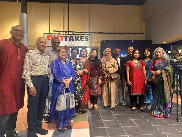 Picture13 - Toronto Bangla Town | Digital Bangla Weekly Magazine Group of about fifteen men and women in colorful traditional and modern clothing posing for a group photo inside Outtakes Backstage Bistro, with the venue sign visible in the background.