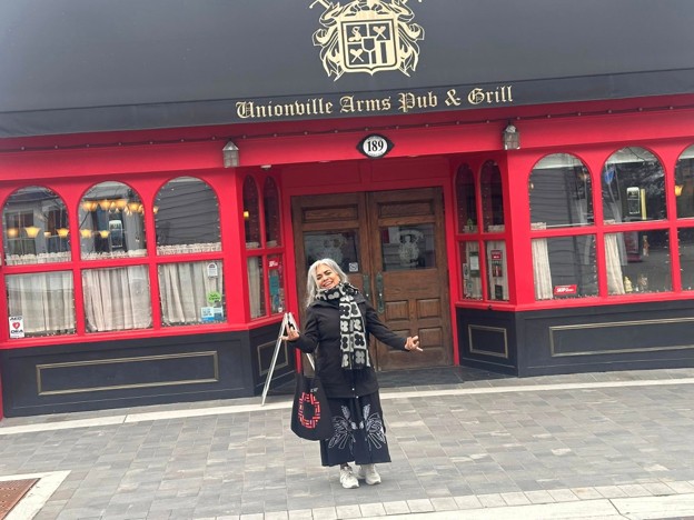 Picture13 - Toronto Bangla Town | Digital Bangla Weekly Magazine Woman posing outside Unionville Arms Pub & Grill, a red-framed storefront with a wooden door.