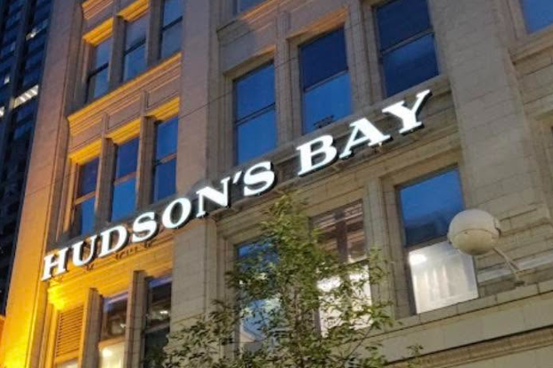 Picture4 - Toronto Bangla Town | Digital Bangla Weekly Magazine Facade of a multi-story building at night with a large illuminated 'HUDSON'S BAY' sign on the façade, and trees in front.