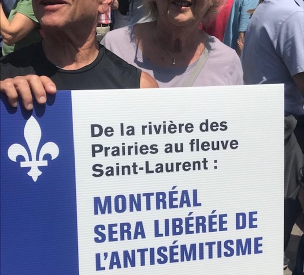 Picture4 - Toronto Bangla Town | Digital Bangla Weekly Magazine Group of people at a demonstration holding a sign in French about Montréal being freed from antisemitism; a blue fleur-de-lis is visible on the left side of the sign.