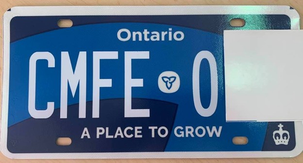 Picture5 - Toronto Bangla Town | Digital Bangla Weekly Magazine Ontario blue license plate with white letters 'CMFEO', trillium logo, and slogan 'A PLACE TO GROW'; right side partially obscured by a white cover.