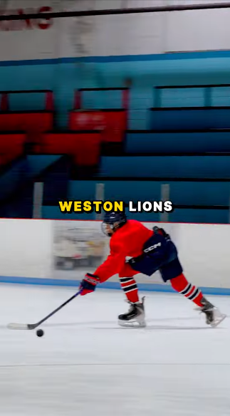 Picture5 - Toronto Bangla Town | Digital Bangla Weekly Magazine Hockey player in a red jersey skates with the puck on an ice rink, arena seating in the background, Weston Lions text overlay.