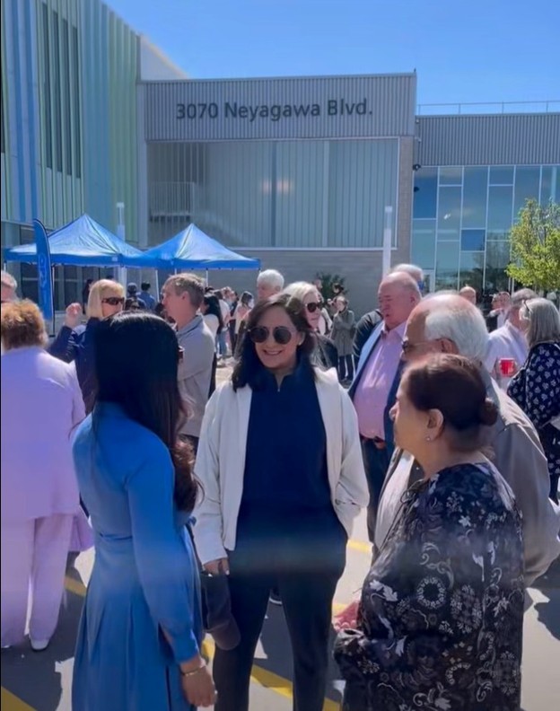 Picture7 - Toronto Bangla Town | Digital Bangla Weekly Magazine Group of people chatting outside a modern building with an address sign reading 3070 Neyagawa Blvd and blue tents in the background.