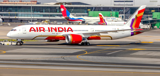 Picture9 - Toronto Bangla Town | Digital Bangla Weekly Magazine Air India passenger jet taxiing on the tarmac with a modern terminal in the background, white fuselage with red Air India branding and red engines.
