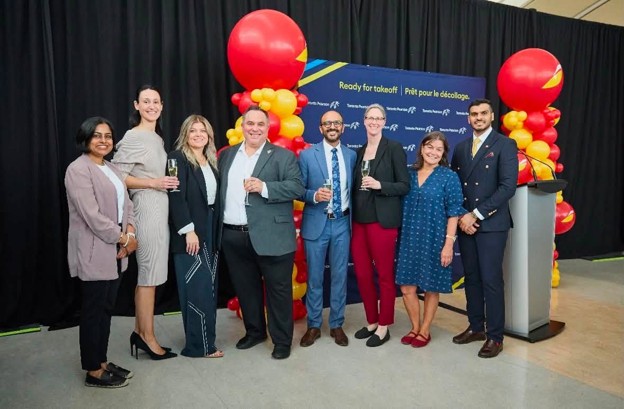 Picture4 - Toronto Bangla Town | Digital Bangla Weekly Magazine Group of eight professionals posing for a photo at a corporate event with red and yellow balloons in the background.