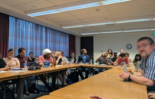 Picture6 - Toronto Bangla Town | Digital Bangla Weekly Magazine Group of people seated around a long conference table in a meeting room, some looking toward the camera.
