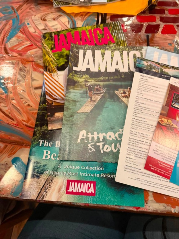 Picture9 - Toronto Bangla Town | Digital Bangla Weekly Magazine Travel brochures for Jamaica on a colorful table, showing turquoise water, a raft, and bold 'JAMAICA' headlines.